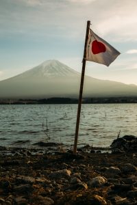 Japan flag pictured in front of a mountain and a lake.